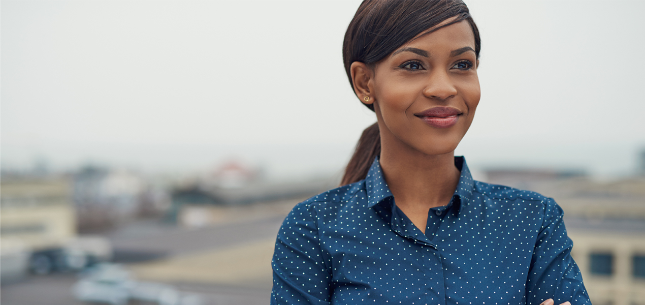Photo of a confident black women in a button-up shirt.