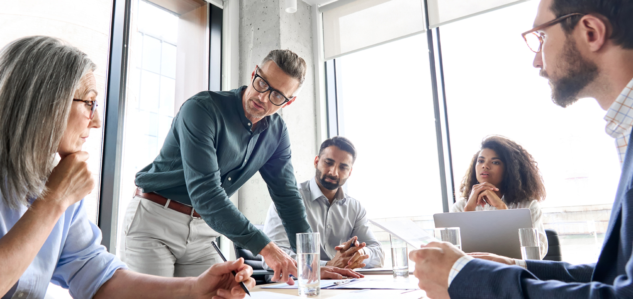 A diverse group of business colleagues at a meeting table with two individuals shaking hands.A diverse group of business colleagues at a meeting table with two individuals shaking hands.