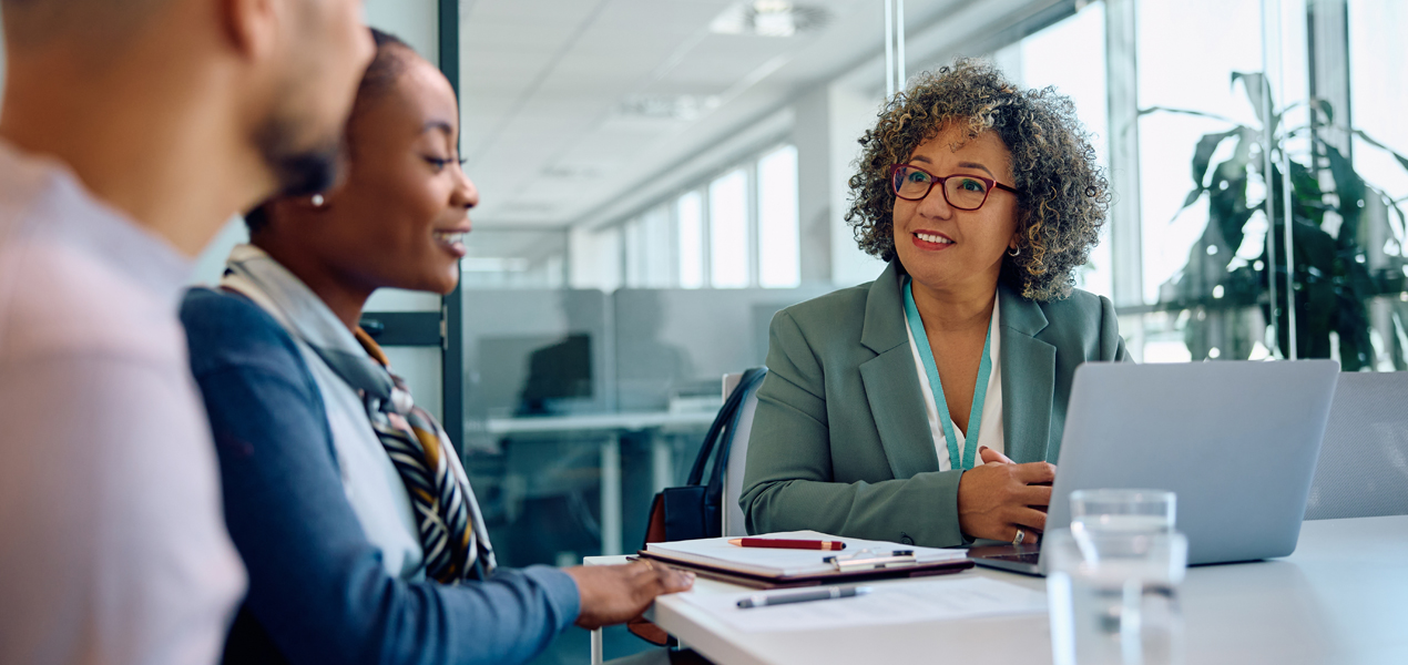 A woman converses with two people at a meeting, contributing to the dialogue and exchanging insights.